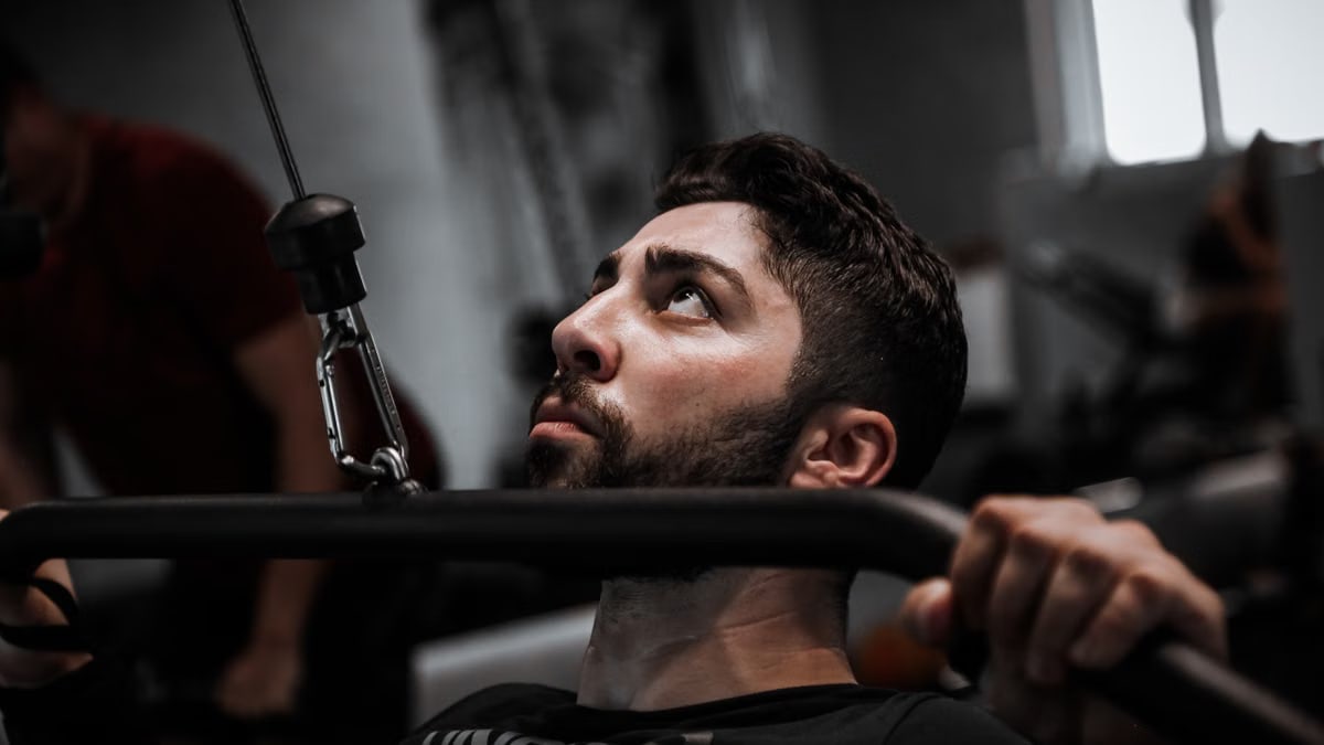 Muscular man working out with determination on gym equipment.